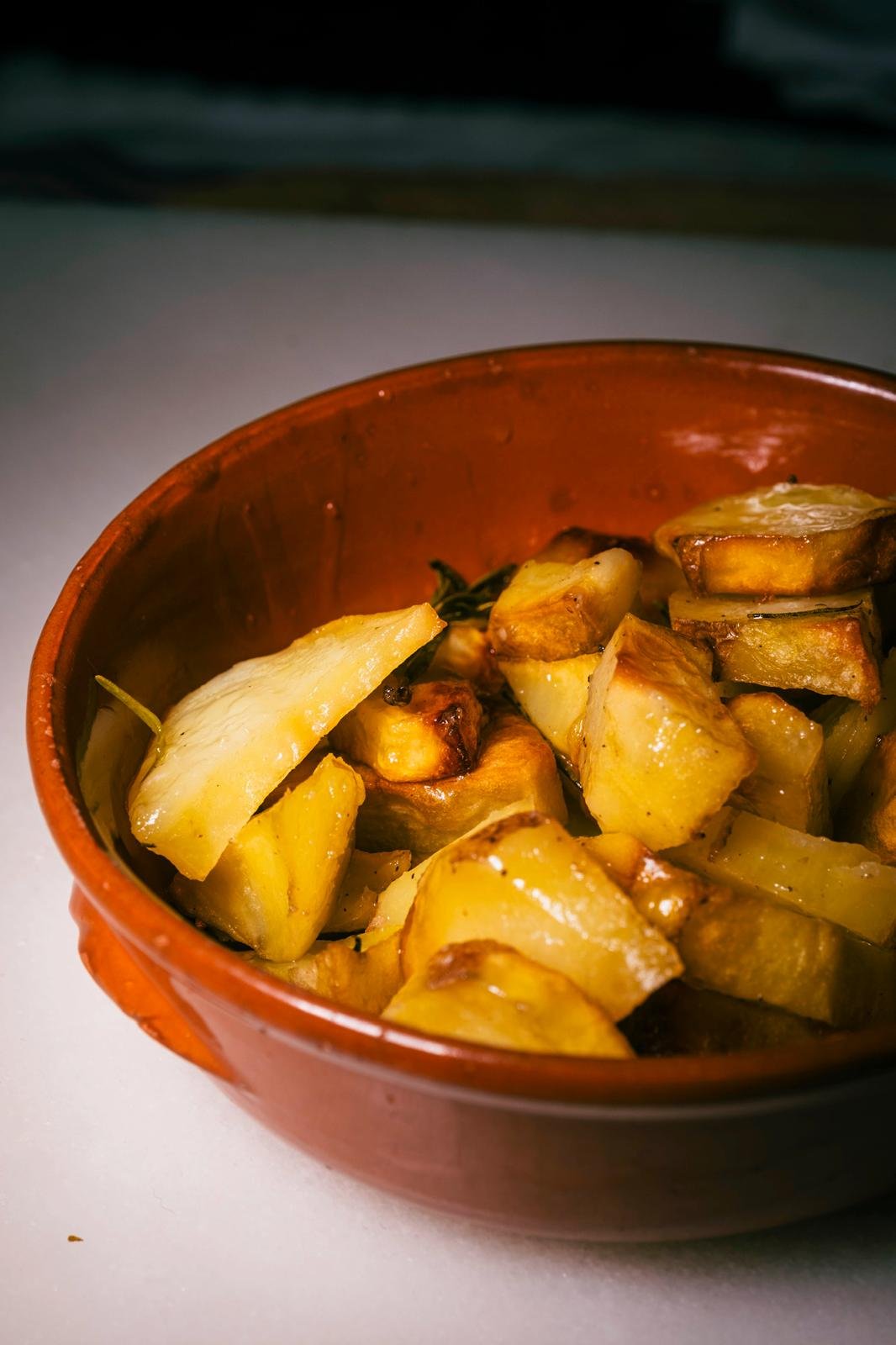 Patate arrosto dorate servite in una ciotola di terracotta